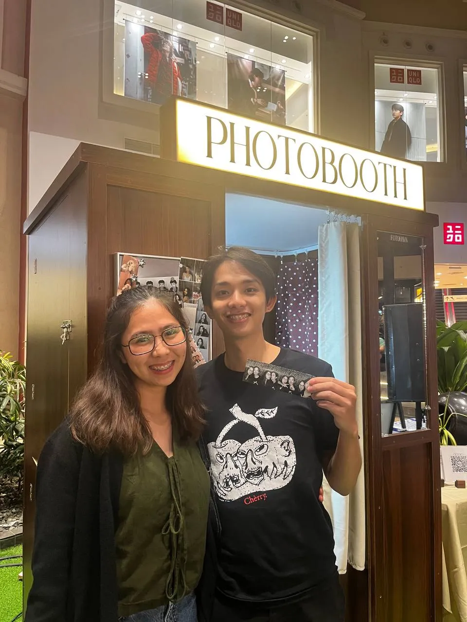 Two guests smiling together outside the cream-curtained booth.
