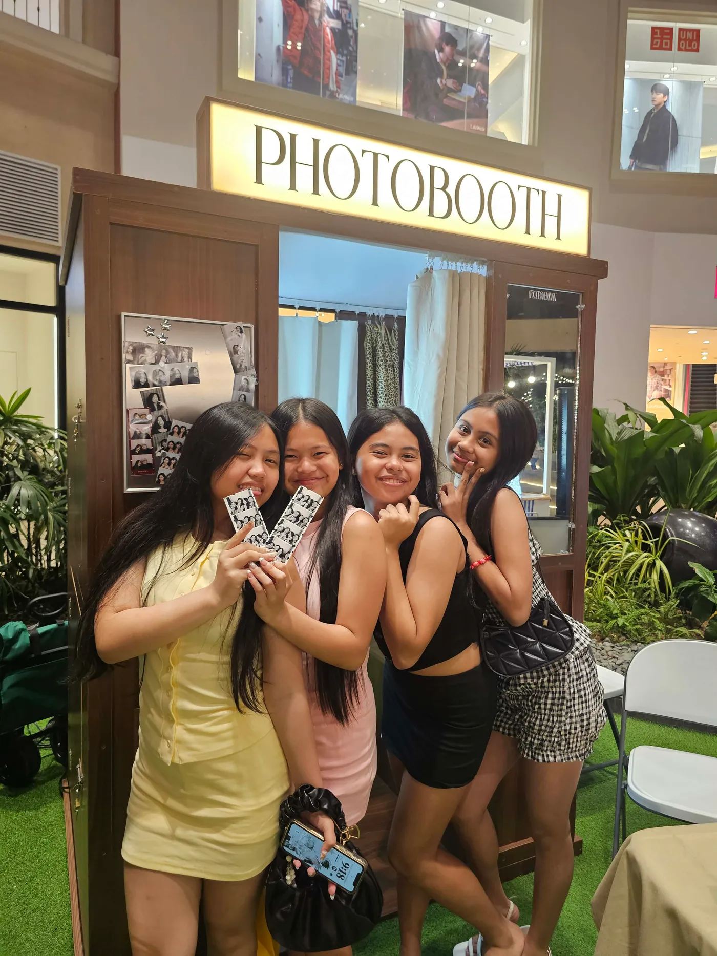 Friends laughing and holding their photographs outside the booth.
