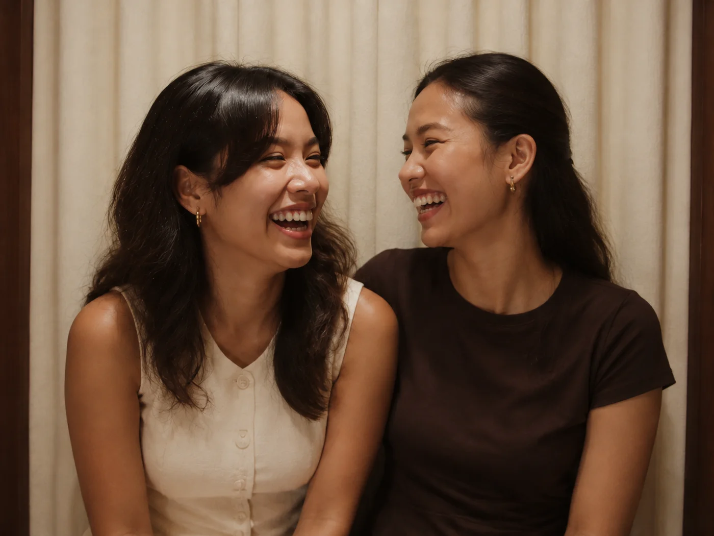 Two friends laughing together against the cream backdrop inside the FOTOHAVN booth.