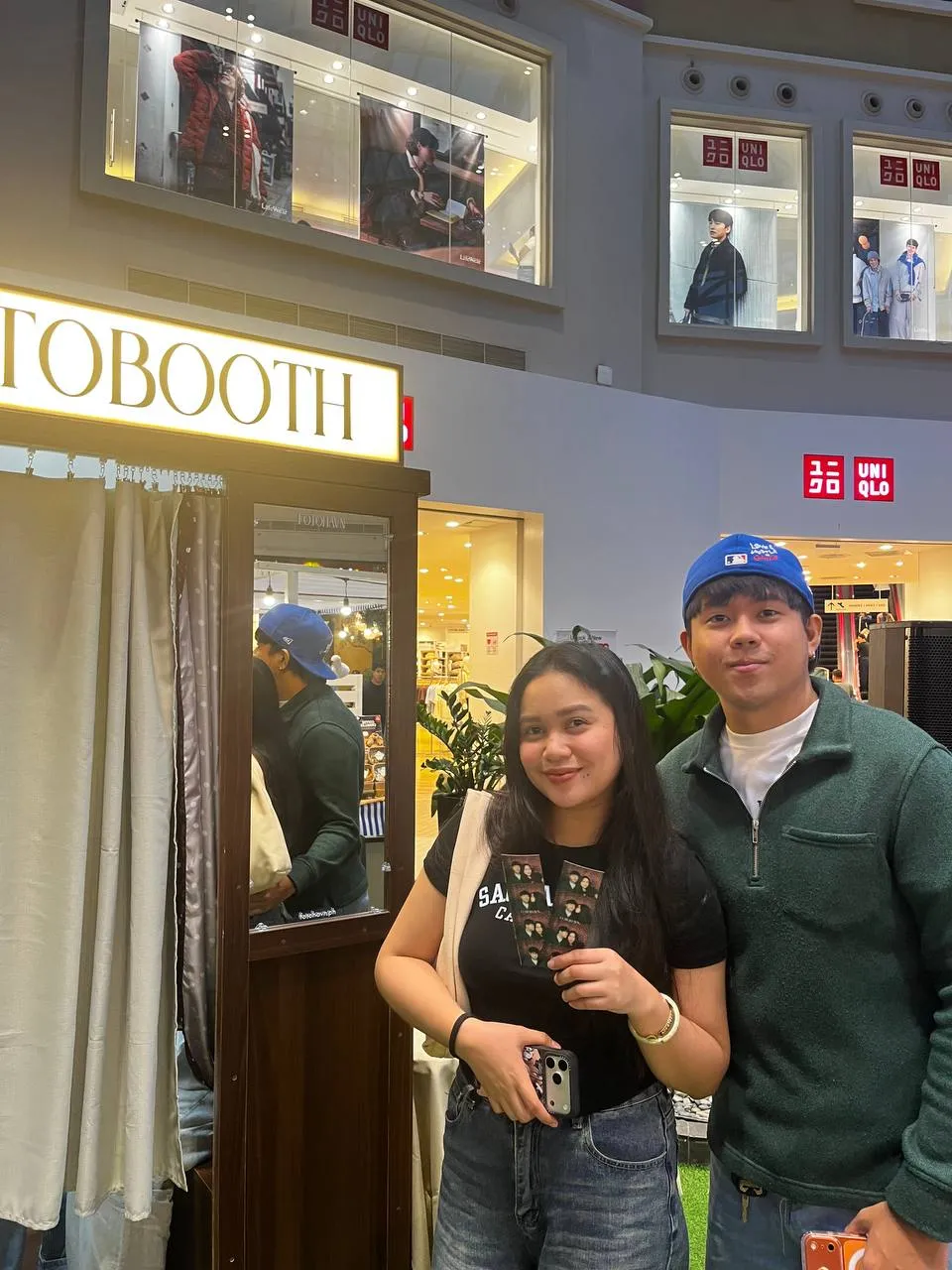 Two guests, one wearing a blue cap, holding their photographs outside FOTOHAVN.