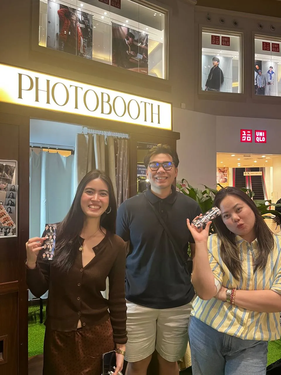 Three guests standing together in front of the cream-curtained booth.
